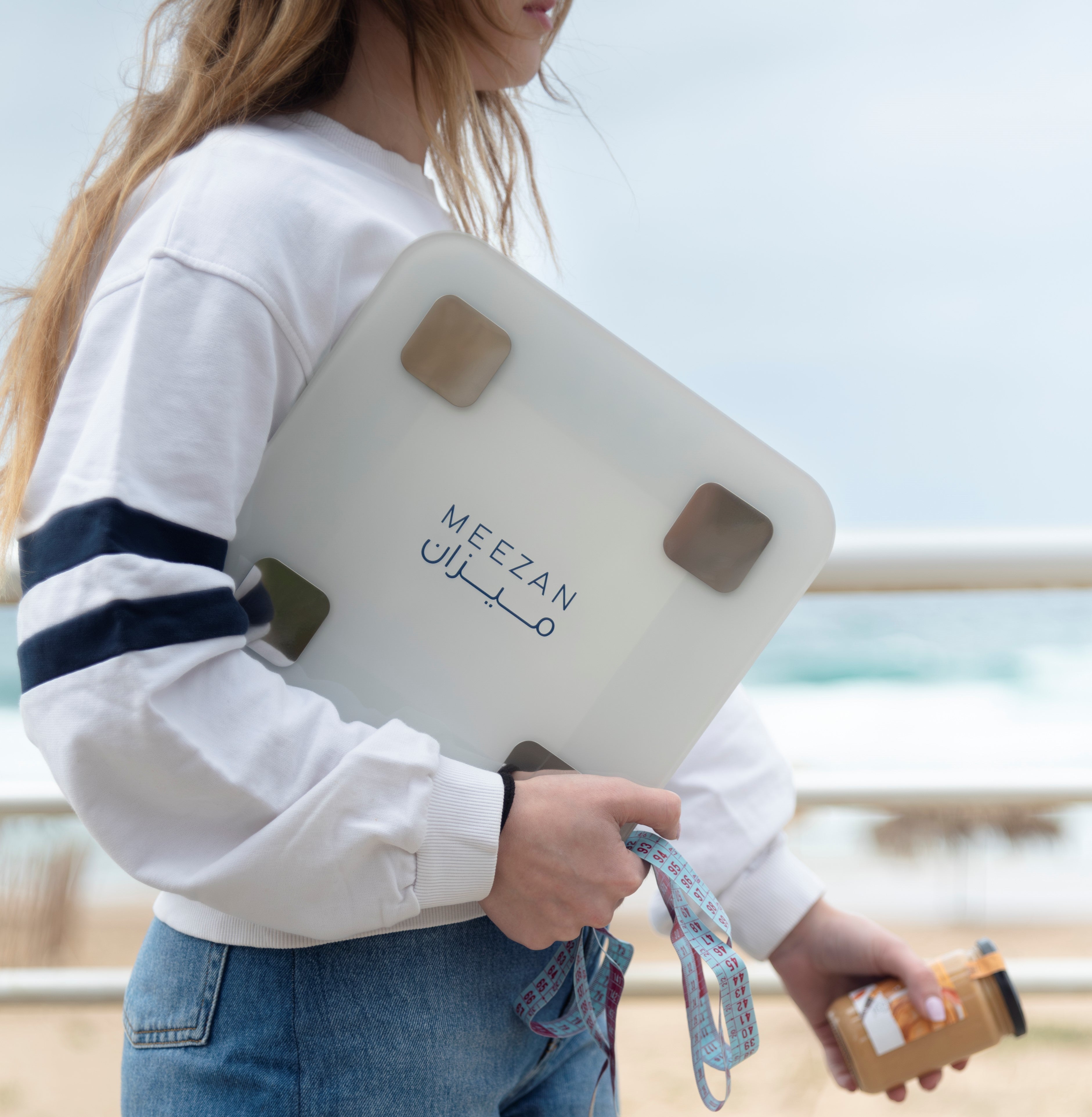 a blonde young girl showing the limited offer that Meezan the brand is doing which is. get a BMI Analyzer today and get with it a free organic peanut butter jar, a measuring tape, an ebook made by Meezan which is a diet guide that has an introduction on all aspects of diets 